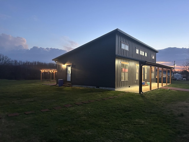 view of side of home featuring a patio area, a lawn, board and batten siding, and entry steps