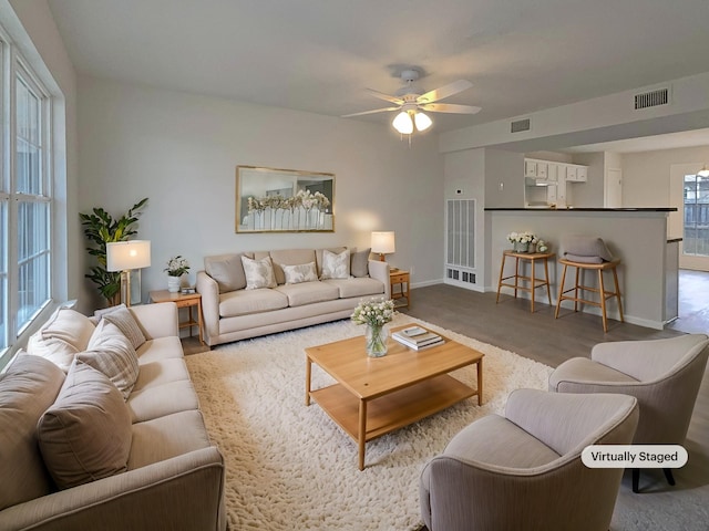 living area featuring visible vents, baseboards, and a ceiling fan