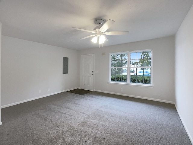 unfurnished room featuring electric panel, ceiling fan, baseboards, and dark colored carpet