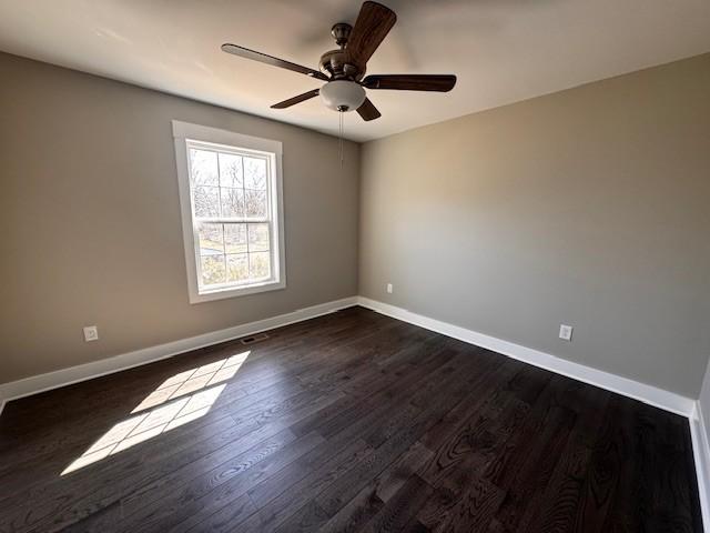 unfurnished room featuring baseboards, dark wood-type flooring, and a ceiling fan