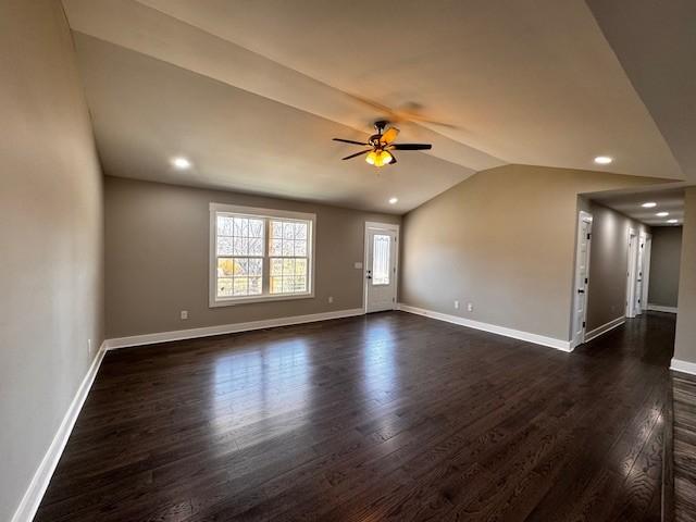 empty room with dark wood finished floors, vaulted ceiling, and baseboards