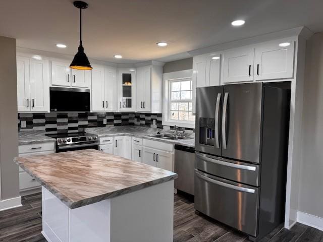 kitchen with dark wood-style flooring, stainless steel appliances, decorative backsplash, and a sink