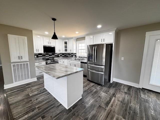 kitchen featuring dark wood-type flooring, tasteful backsplash, stainless steel appliances, white cabinets, and light countertops