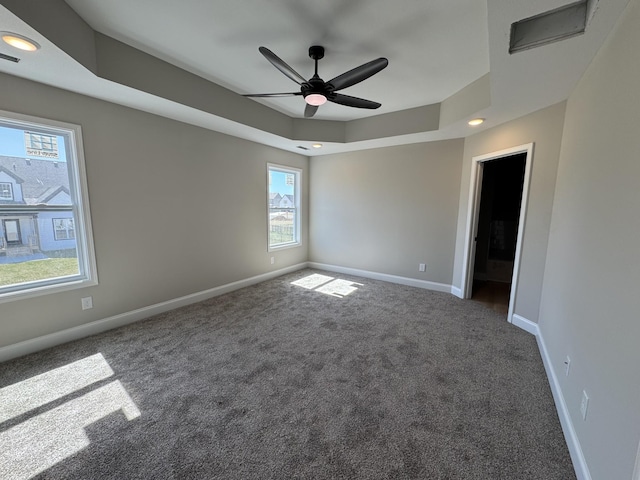 empty room featuring visible vents, a raised ceiling, recessed lighting, carpet, and baseboards