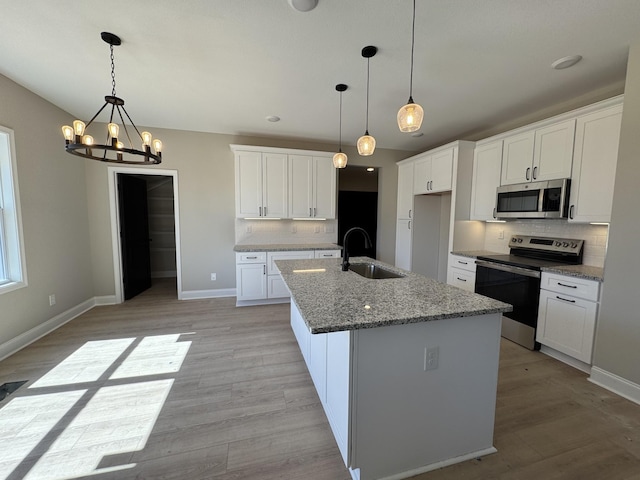 kitchen featuring a sink, stainless steel appliances, light wood-type flooring, and backsplash