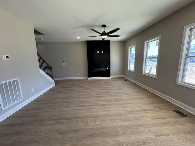 unfurnished living room featuring stairs, plenty of natural light, and visible vents