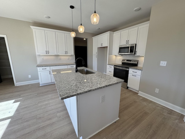 kitchen featuring light wood-style floors, baseboards, appliances with stainless steel finishes, and a sink