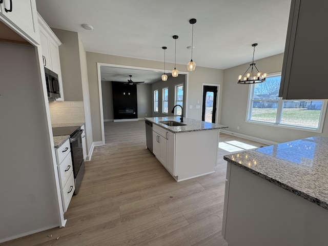 kitchen featuring a healthy amount of sunlight, light wood-type flooring, decorative backsplash, appliances with stainless steel finishes, and a sink