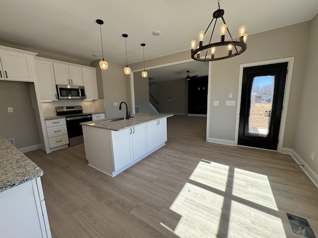 kitchen featuring light stone counters, a sink, white cabinets, appliances with stainless steel finishes, and light wood-type flooring