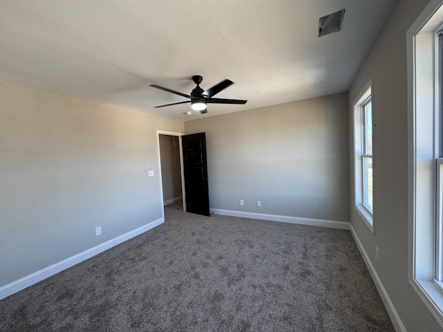 carpeted spare room featuring baseboards and ceiling fan