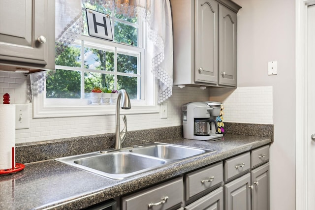 kitchen with dark countertops, gray cabinets, tasteful backsplash, and a sink