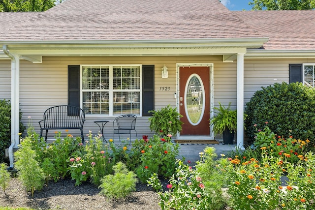 property entrance with covered porch and a shingled roof