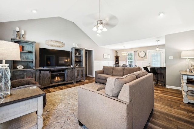 living area featuring a wainscoted wall, wood finished floors, a fireplace, lofted ceiling, and ceiling fan