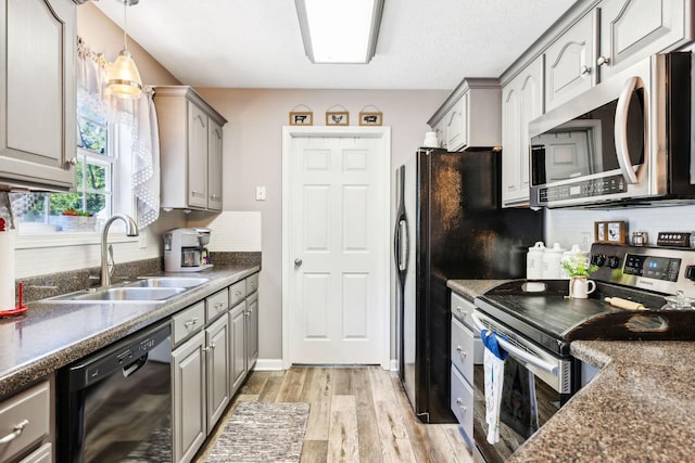 kitchen featuring gray cabinets, stainless steel appliances, light wood-style floors, and a sink