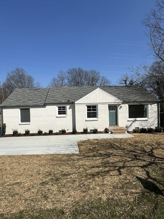 rear view of property with brick siding and roof with shingles