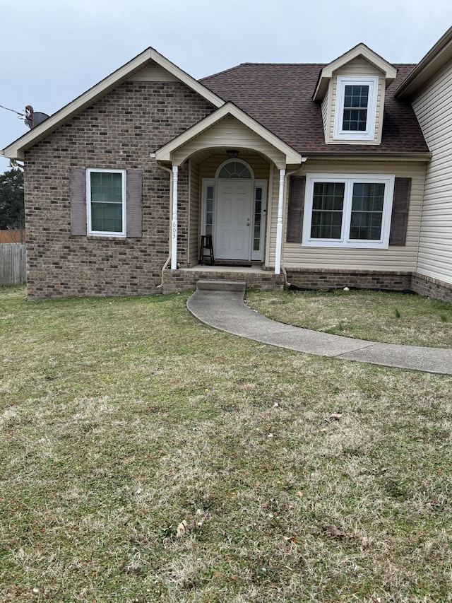 view of front of house featuring brick siding, a front yard, and a shingled roof