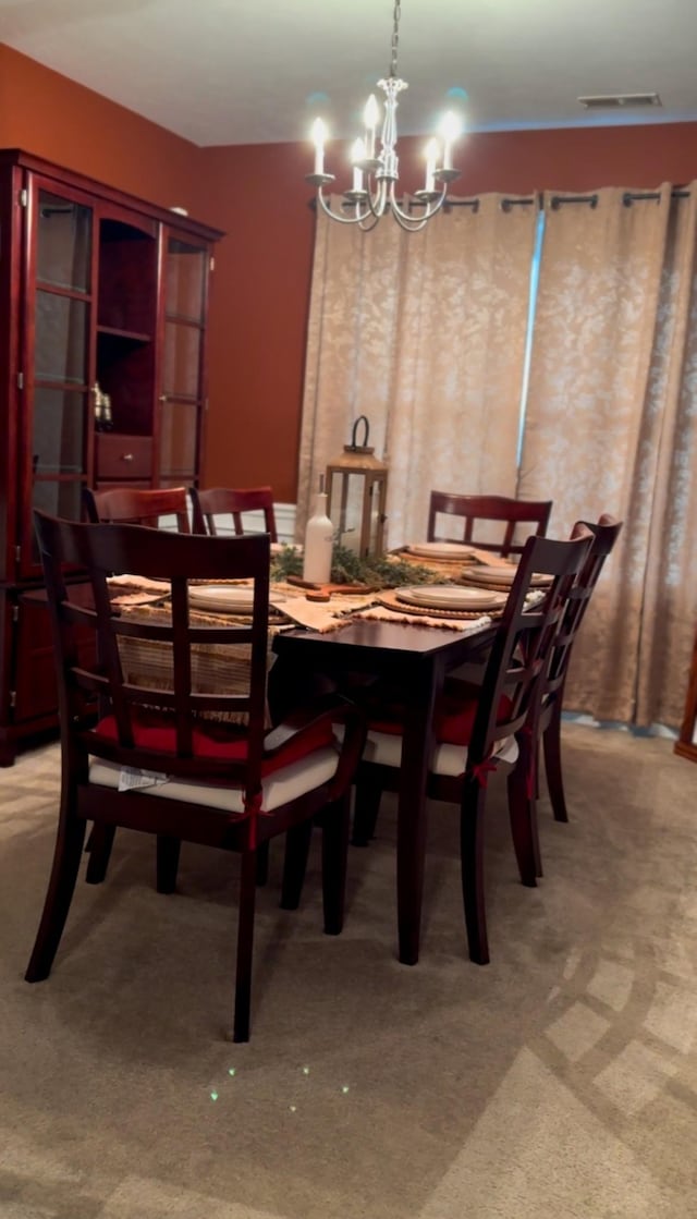 dining room with a notable chandelier, visible vents, and light carpet