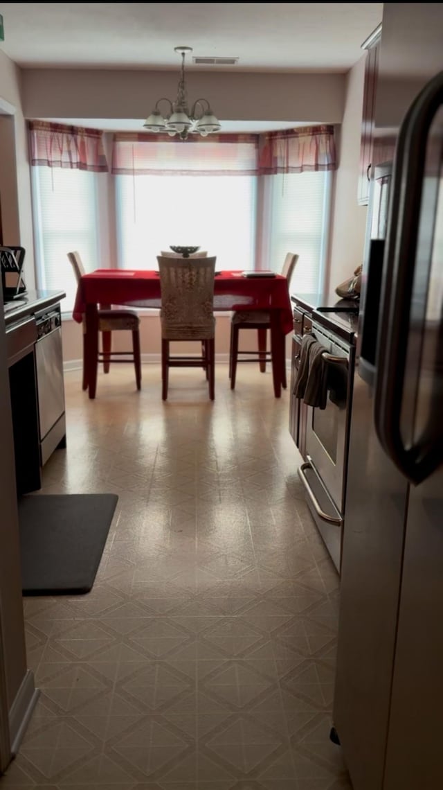 interior space featuring tile patterned floors, baseboards, visible vents, and a chandelier