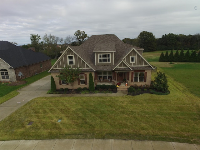 craftsman-style home featuring a front yard, covered porch, and roof with shingles