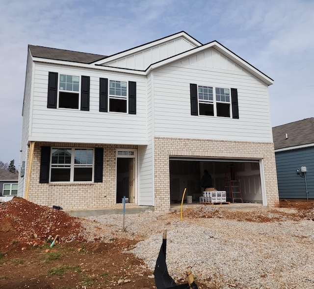 view of front of home featuring driveway, brick siding, board and batten siding, and an attached garage