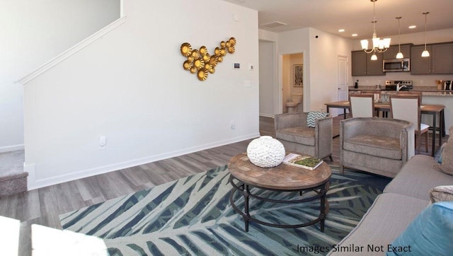 living area featuring recessed lighting, baseboards, a notable chandelier, and dark wood finished floors