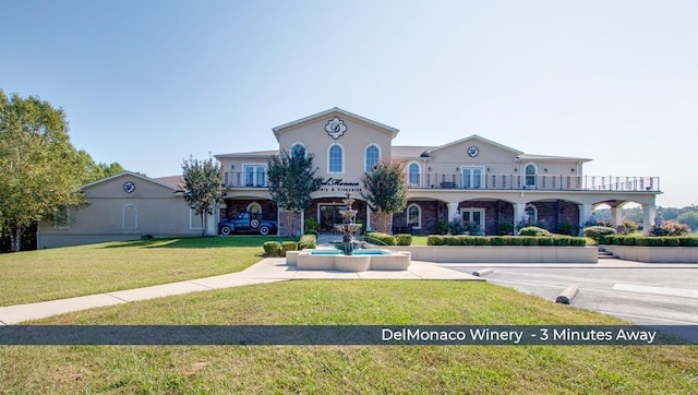 mediterranean / spanish house with stucco siding, a balcony, and a front yard