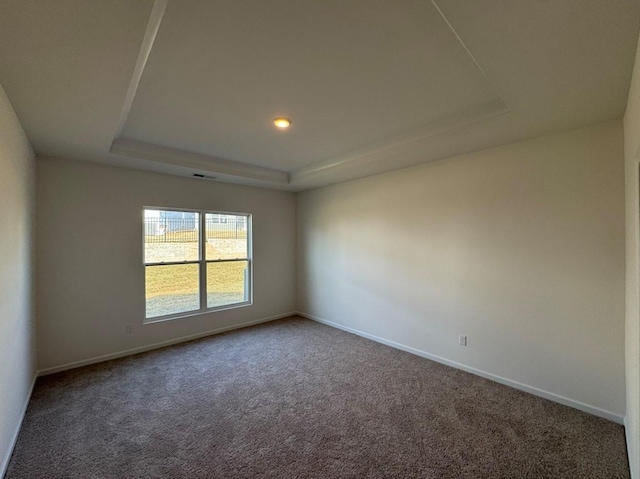 spare room with a tray ceiling, carpet flooring, and baseboards