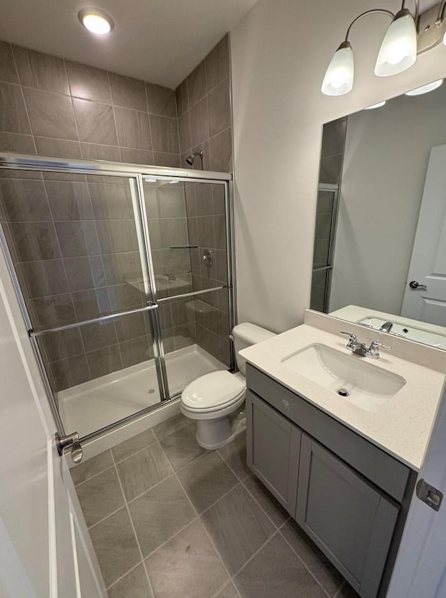 full bathroom featuring vanity, tile patterned floors, toilet, and a stall shower