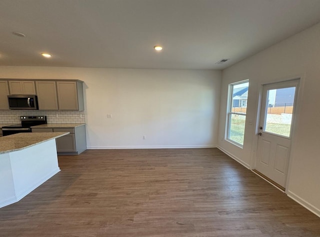 kitchen featuring wood finished floors, visible vents, gray cabinets, appliances with stainless steel finishes, and backsplash