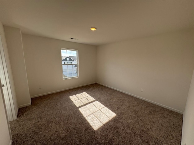 spare room featuring carpet, visible vents, and baseboards