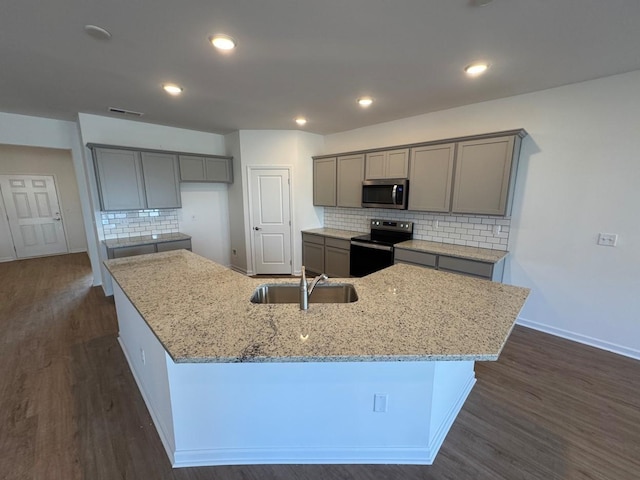 kitchen with a large island, gray cabinets, appliances with stainless steel finishes, and a sink