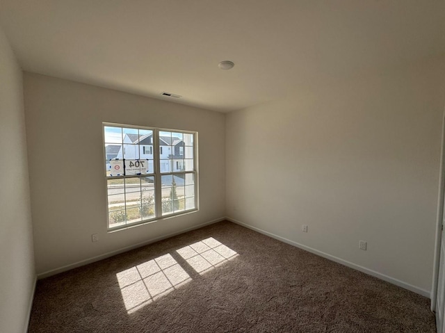 empty room featuring baseboards, visible vents, and carpet floors