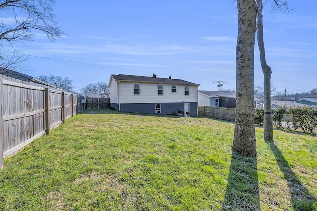 rear view of property featuring a fenced backyard and a yard