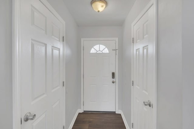 doorway featuring dark wood-type flooring and baseboards