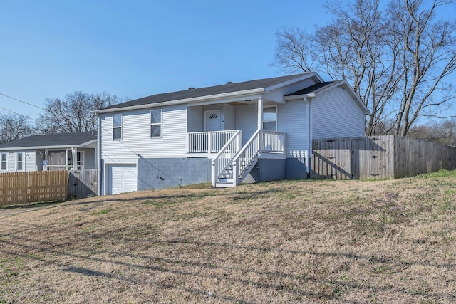 rear view of house featuring a lawn, a porch, an attached garage, and fence