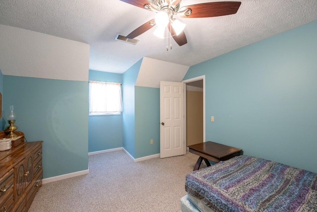 carpeted bedroom with visible vents, a textured ceiling, ceiling fan, and vaulted ceiling