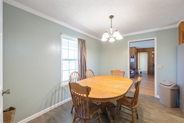 dining area featuring baseboards, ornamental molding, an inviting chandelier, wood finished floors, and a textured ceiling