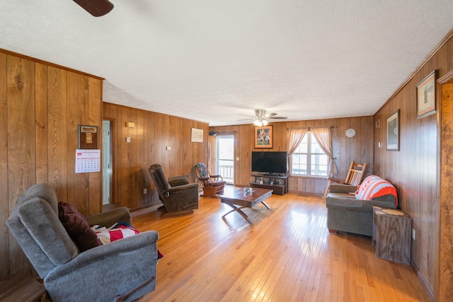 living room with light wood finished floors, a textured ceiling, and a ceiling fan