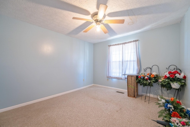 spare room with a ceiling fan, baseboards, a textured ceiling, and carpet flooring