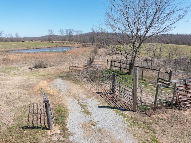 exterior space featuring a rural view, a gate, fence, and a water view