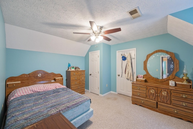 carpeted bedroom featuring vaulted ceiling, a ceiling fan, visible vents, and a textured ceiling