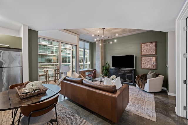 living area featuring baseboards, concrete flooring, and a chandelier