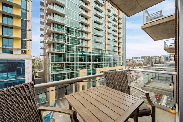 balcony with outdoor dining area and a city view