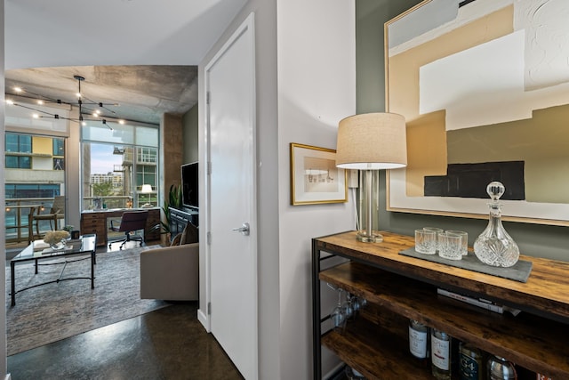 hallway with track lighting and concrete flooring