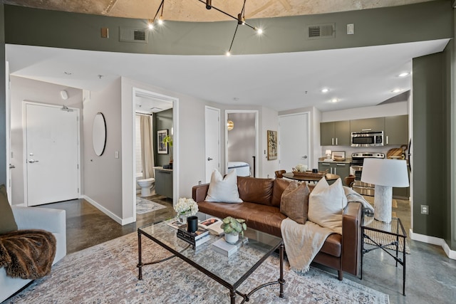 living area featuring visible vents, baseboards, and concrete flooring