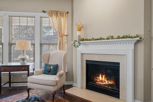 living area with a premium fireplace, baseboards, and wood finished floors