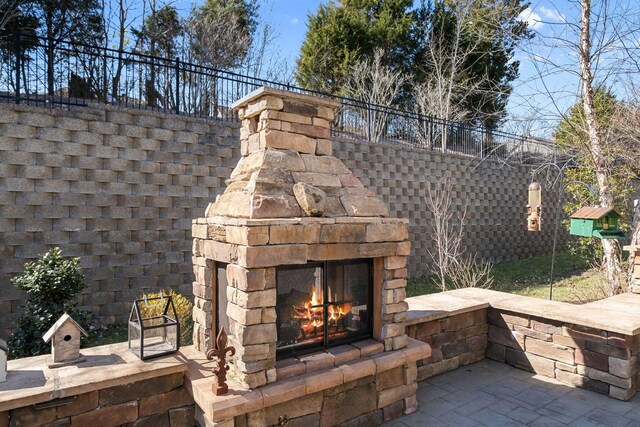 view of patio with an outdoor stone fireplace and fence