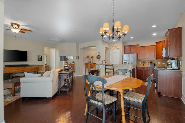 dining room with baseboards, dark wood finished floors, recessed lighting, ceiling fan with notable chandelier, and arched walkways