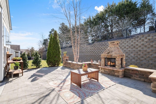 view of patio featuring an outdoor stone fireplace and fence