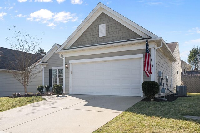 view of front of home with a front yard, a garage, driveway, and central AC